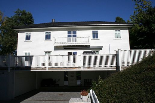 Hvit enebolig med balkong og terasse