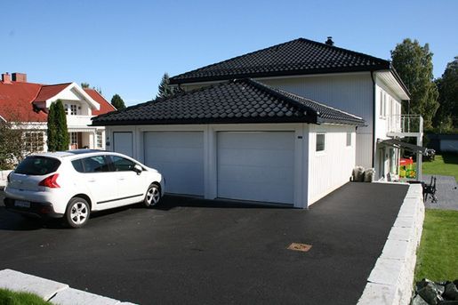 Hvit enebolig med garasje og parkeringsplass utenfor