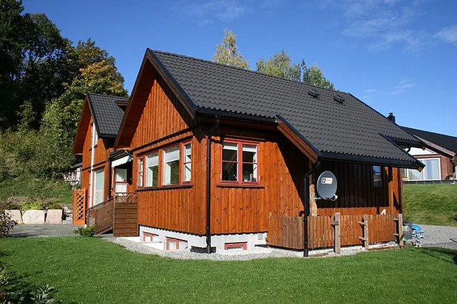 Brun enebolig med opparbeidet hage