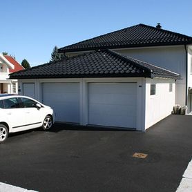 Hvit enebolig med garasje og parkeringsplass utenfor